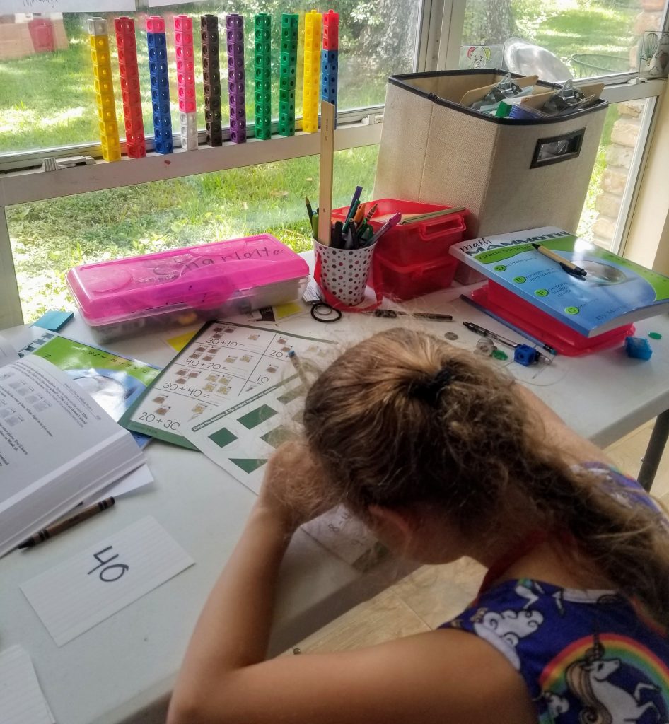 A girl doing schoolwork at a table - tips for homeschooling kindergarten
