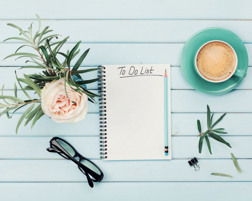 A flower, coffee cup, pair of glasses, and notebook sitting on a table. - tips for overwhelmed moms