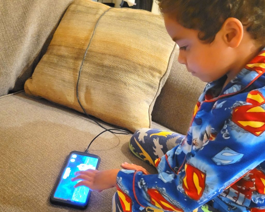 Boy playing LuvBug Learning app on the phone.