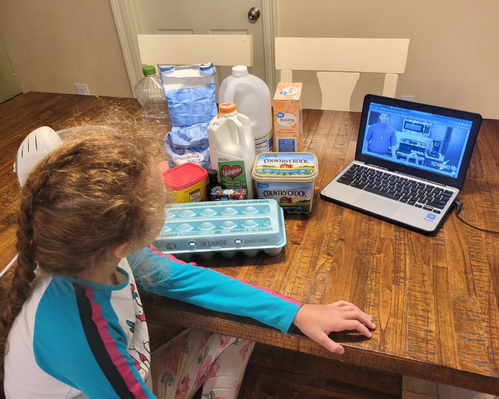 Girl watching Sparketh online art classes for kids on a computer with baking ingredients next to her.